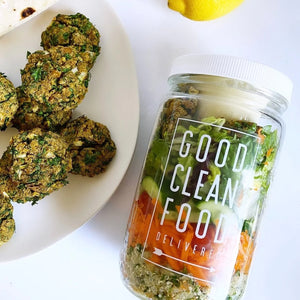 Jar labeled 'Good Clean Food Delivered' with salad ingredients, next to a plate of falafel.