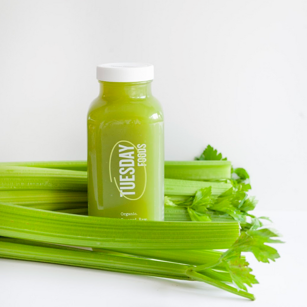 Green juice bottle with celery on a white background