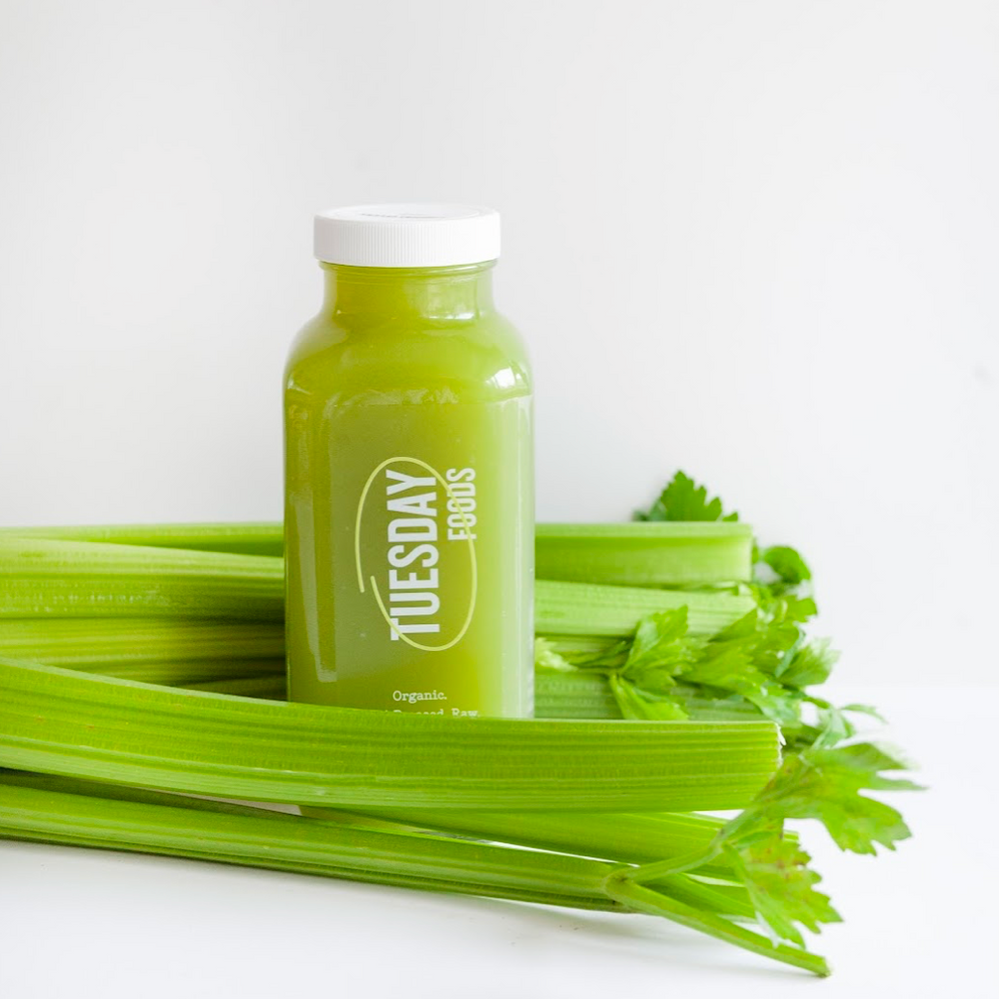 Green juice bottle with celery on a white background